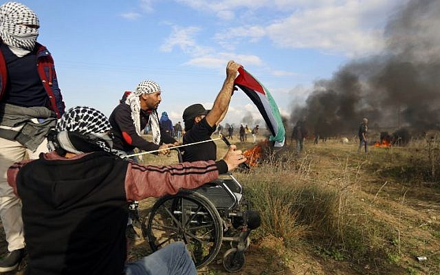 Wheelchair-bound Palestinian demonstrator Ibrahim Abu Thurayeh, waving a Palestinian flag during a protest along the Gaza-Israel border on December 15, 2017, as clashes with Israeli security forces against Washington's recognition of Jerusalem as Israel's capital intensified. (MOHAMMED ABED / AFP)