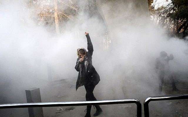 An Iranian woman raises her fist amid the smoke of tear gas at the University of Tehran during a protest driven by anger over economic problems, in the capital Tehran on December 30, 201(AFP PHOTO / STR)