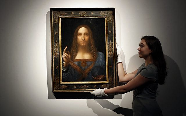 In this October 24, 2017, photo, an employee poses with Leonardo da Vinci's "Salvator Mundi" on display at Christie's auction rooms in London. (AP Photo/Kirsty Wigglesworth)