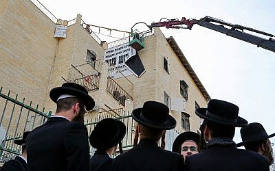 Beit Shemesh municipal workers take down “modesty” signs in the city on December 11, 2017. (Yaakov Lederman/Flash90)