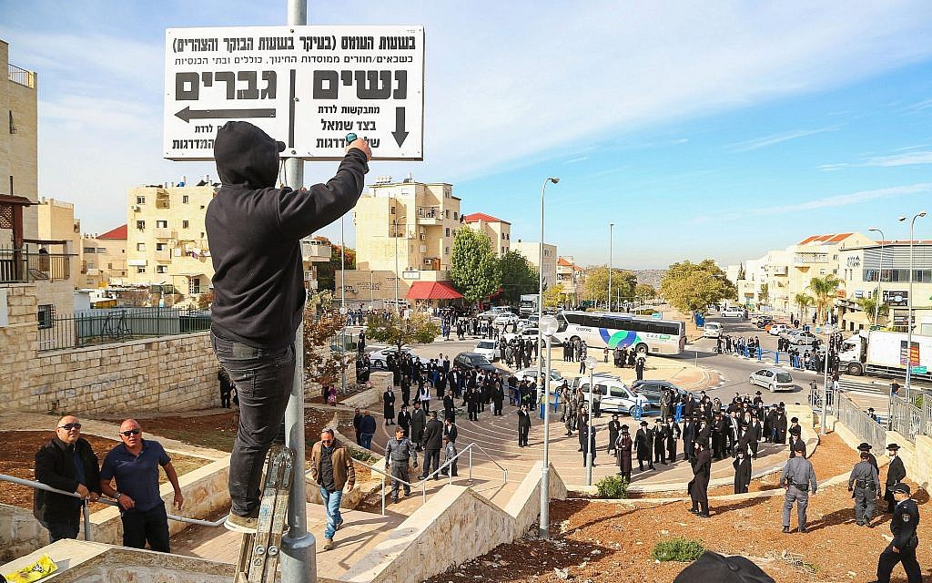 Police stand guard as Beit Shemesh municipal workers take down signs instructing men and women of an ultra-Orthodox neighborhood to walk on different sides of the street, December 11, 2017. (Yaakov Lederman/Flash90)