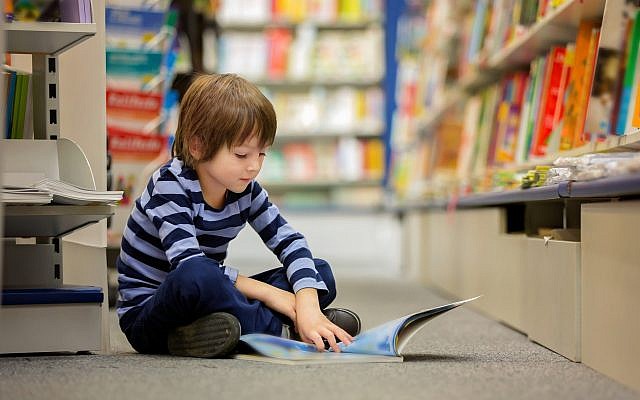 Illustrative image of a boy, sitting in a book store, reading (tatyana_tomsickova/ IStock by Getty Images)