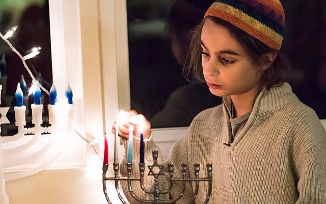 Lahav Zaken lights the Hanukkah menorah (Hillary Zaken)