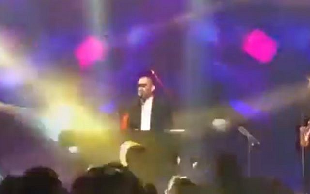 Ultra-Orthodox singer Yonatan Razel covers his eyes with masking tape to avoid seeing women dancing at the foot of the stage on December 3, 2017. (Screen capture: Twitter video)
