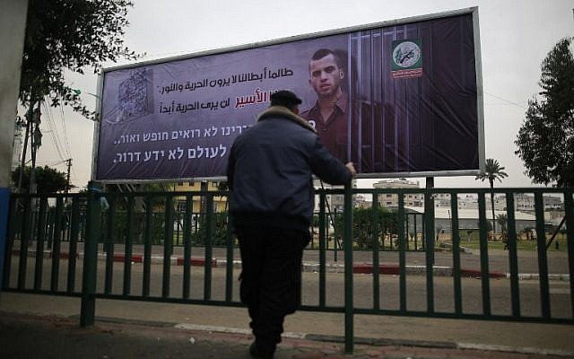 A Palestinian Hamas police officer looks at a billboard bearing a portrait of slain Israeli soldier Oron Shaul in Gaza City on December 29, 2017. The writing in Arabic reads: ''As long as our heroes don't see freedom and light: This captive will never see freedom'' (AFP PHOTO / MOHAMMED ABED)