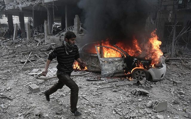 A Syrian man runs past a burning vehicle following reported bombardment by Syrian and Russian forces in the rebel-held town of Hamouria, in the Eastern Ghouta, on January 6, 2018. (AFP/ABDULMONAM EASSA)