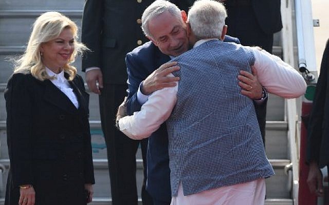 Indian Prime Minister Narendra Modi, right, embraces Prime Minister  Benjamin Netanyahu, as the Israeli leader's wife, Sara, watches on their arrival at the Air Force Station in New Delhi, on January 14, 2018. (PRAKASH SINGH/AFP)