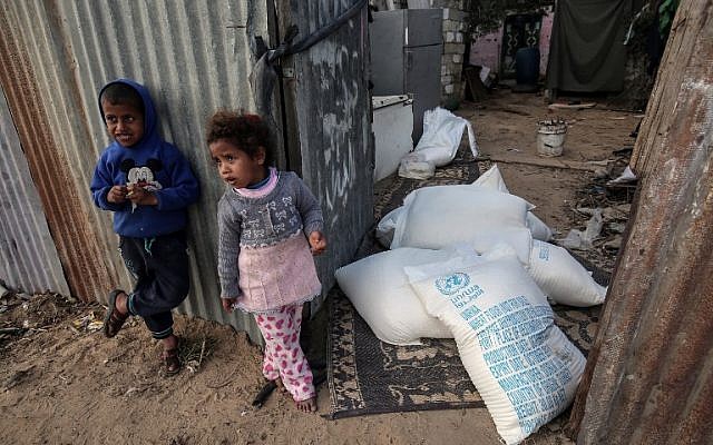 Palestinian children stand next to bags of food aid provided by the UN agency for Palestinian refugees in the Rafah refugee camp in the southern Gaza Strip on January 24, 2018. (AFP Photo/Said Khatib)