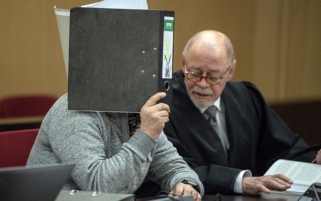 The defendant accused of a bombing at the Dusseldorf-Wehrhahn station targeting Jewish immigrants in the year 2000 hides his face behind a folder and sits next to his lawyer as he waits for the start of his trial on January 25, 2018 in Dusseldorf, western Germany. (AFP Photo/dpa/Federico Gambarini)