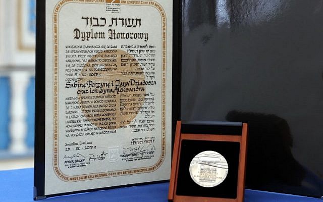 A general view shows the Righteous Among the Nations award that was received by Alicja Mularska (C), the daughter of the late Polish couple Jan Dziadosz and Sabina Perzyna during a posthumous ceremony honouring them and their son Aleksandr Dziadosz at the Yad Vashem Museum on January 30, 2018. / AFP PHOTO / THOMAS COEX