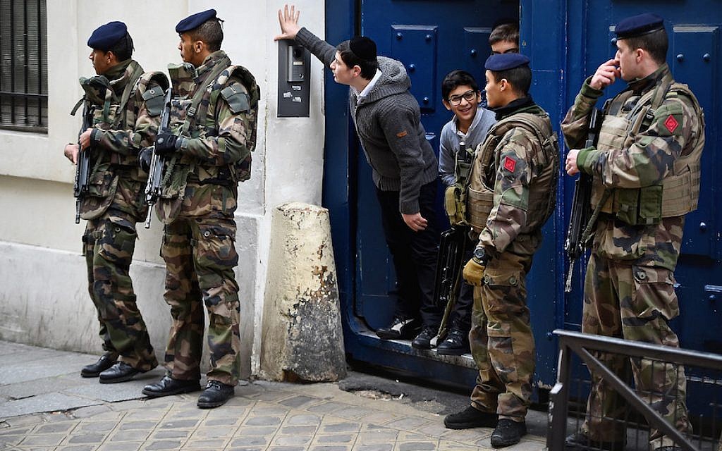 Illustrative: Children look out from a doorway as armed soldiers patrol outside a school in the Jewish quarter of the Marais district in Paris, January 13, 2015. (Jeff J. Mitchell/Getty Images/via JTA)