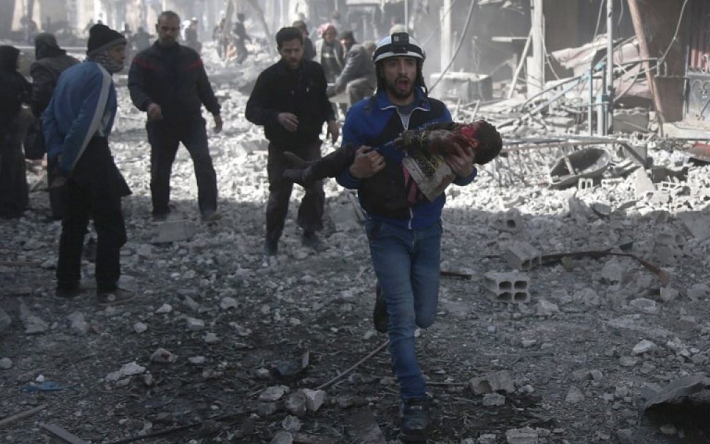 A Syrian civil defense member carries an injured child rescued from between the rubble of buildings following government bombing in the rebel-held town of Hamouria, in the besieged Eastern Ghouta region on the outskirts of the capital Damascus, on February 19, 2018. (AFP PHOTO / ABDULMONAM EASSA)