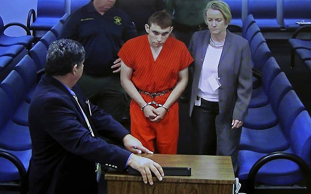 A video monitor shows school shooting suspect Nikolas Cruz, left, with public defender Melisa McNeille, making an appearance before Judge Kim Theresa Mollica in Broward County Court, Thursday, Feb. 15, 2018, in Fort Lauderdale, Fla. Cruz is accused of opening fire Wednesday at the school killing more than a dozen people and injuring several. (Susan Stocker/South Florida Sun-Sentinel via AP, Pool)