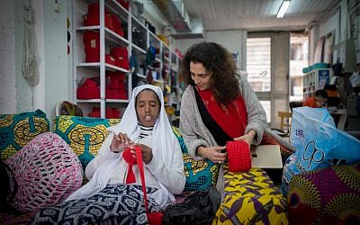 Dr Diddy Mymin Kahn, co-founder and director of the Kuchinate collective, looks on as Selam crochets a basket at the Kuchinate workshop in Tel Aviv, on January 3, 2018. (Miriam Alster/Flash90)