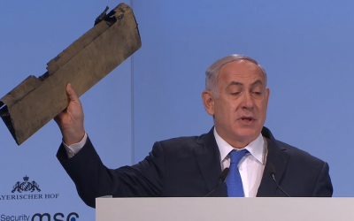 Prime Minister Benjamin Netanyahu waves part of an Iranian drone downed in Israeli airspace on February 10, 2018, during a speech on the third day of the 54th Munich Security Conference (MSC) held at the Bayerischer Hof hotel, in Munich, southern Germany, on February 18, 2018. (Screen capture)