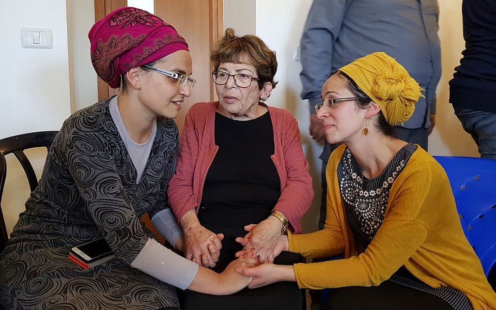 Yael Shevach (L), the wife of Raziel Shevach who was gunned-down in a  January 9 terror attack near the Havat Gilad outpost consoles Miriam Ben-Gal, the wife of Itamar Ben-Gal, who was stabbed to death in a February 5 terror attack. Photo taken at Ben-Gal home on February 6, 2018. In the middle is Miriam's grandmother Esther. (Courtesy)