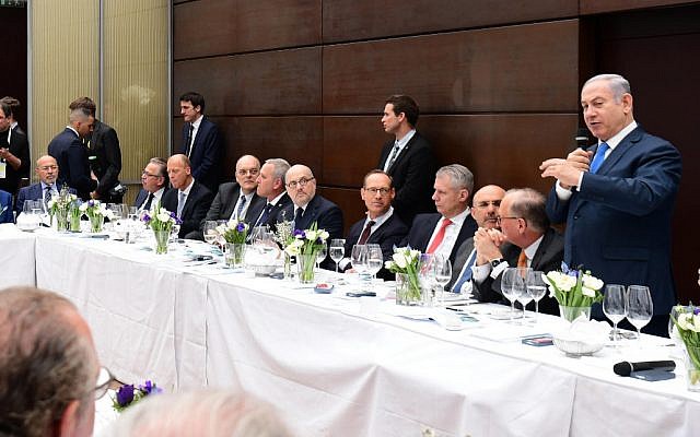Prime Minister Benjamin Netanyahu, right, addresses dozens of senior business leaders, encouraging them to invest in Israel, ahead of the Munich Security Conference, February 16, 2018. (Amos Ben Gershom/GPO)