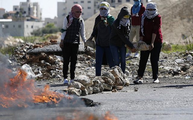 Palestinian demonstrators carry stones during clashes with Israeli soldiers on March 12, 2018 in the West Bank town of Birzeit, near Ramallah. (AFP/ABBAS MOMANI)