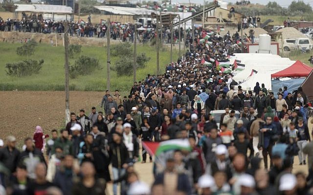 Palestinians march past a tent city erected along the border with Israel east of Gaza City in the Gaza strip on March 30, 2018. (AFP PHOTO / MAHMUD HAMS)