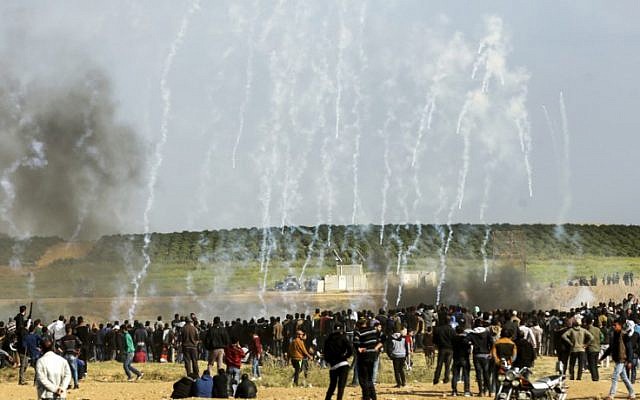 Palestinian protestors run for cover from tear gas fired by Israeli security forces during clashes following a demonstration commemorating Land Day, near the border with Israel, east of Gaza City, on March 30, 2018. (Mahmud Hams/AFP)