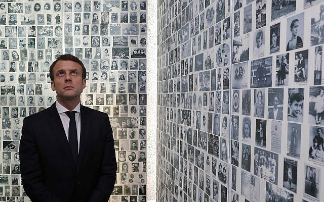 In this photo from April 30, 2017, Emmanuel Macron looks at some of the 2,500 photographs of young Jews deported from France, during a visit to the Shoah memorial in Paris, France. (Philippe Wojazer/Pool Photo via AP, File)