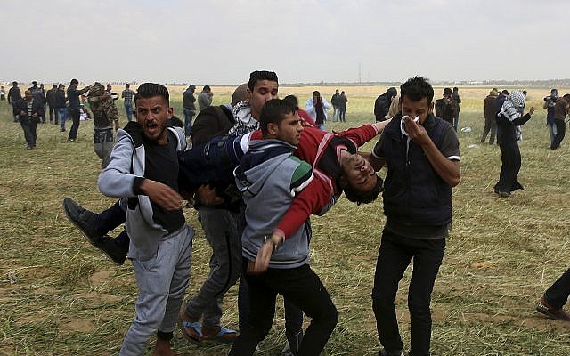 Illustrative image of Palestinian protesters evacuating a wounded youth during clashes with Israeli troops along the Gaza Strip border with Israel, east of Khan Younis, March 30, 2018. (AP Photo/Adel Hana)
