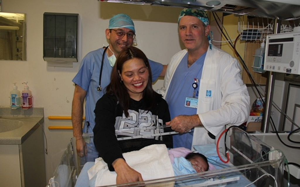 Dr. Julius Golender, back left, and Dr. Gavri Sagi pose for a picture with Filipina mother Nina and her baby Francis Joseph, who was born with a rare heart defect and whose life they saved in Jerusalem's Hadassah Hospital Ein Kerem in February 2018. (Hadassah Hospital)