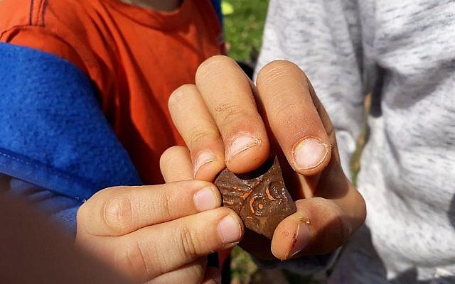 Pupils from Benzion Netanyahu school in the West Bank settlement of Barkan hold a piece of 1,500 pottery that was once part of an oil lamp. (courtesy)