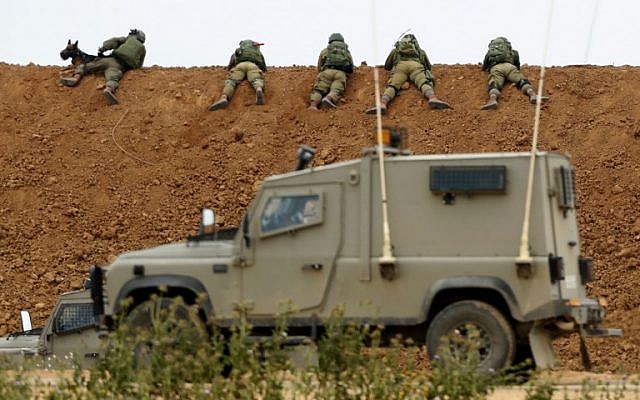 Illustrative: Israeli soldiers take aim, as they lie on an earth barrier along the border with the Gaza Strip, near the southern Israeli kibbutz of Nahal Oz, on March 30, 2018. (Jack Guez/AFP)