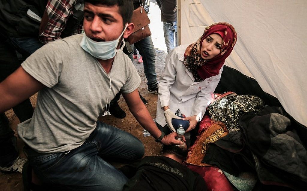 Medical staff help an injured Palestinian man at an emergency medical tent after clashes with Israeli security forces in the southern Gaza Strip on April 1, 2018. (AFP  / SAID KHATIB)