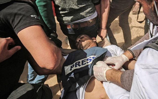 Demonstrators assist injured Palestinian journalist Yasser Murtaja during clashes with Israeli security forces, following a protest near the border with Israel, east of Khan Yunis in the southern Gaza Strip, on April 6, 2018. Murtaja later died of his wounds. (AFP/Said Khatib)
