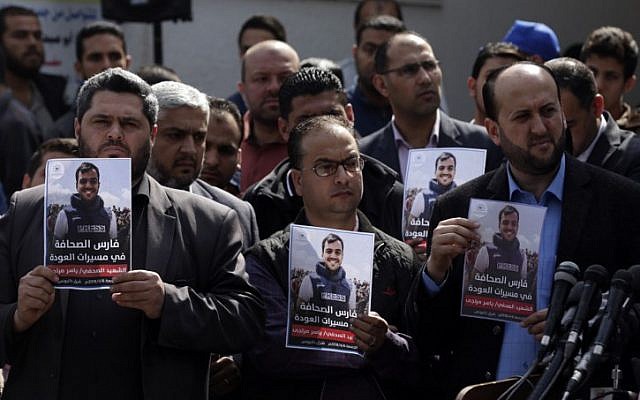 Palestinian journalists carry a portrait of journalist Yasser Murtaja, during his funeral in Gaza City on April 7, 2018. (AFP PHOTO / MAHMUD HAMS)