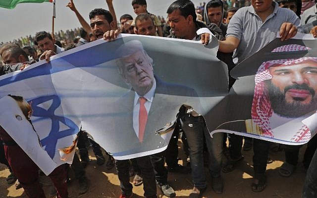 Palestinians prepare to set fire to an Israeli flag and portraits of US President Donald Trump and Saudi Crown Prince Mohammed bin Salman during a protest at the border fence between Israel and the Gaza Strip, April 13, 2018. (AFP/Thomas Coex)