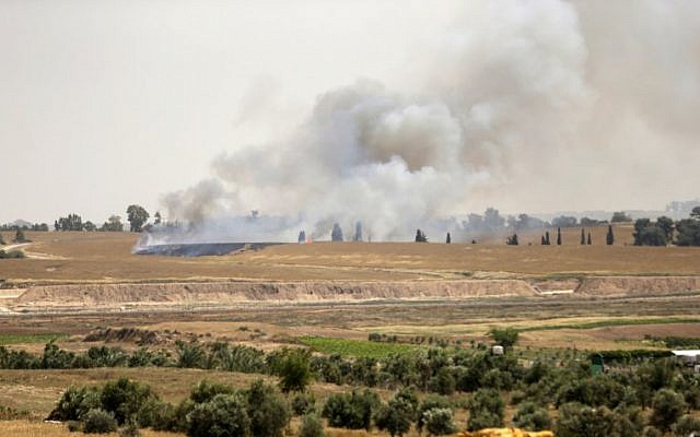 Illustrative: Smoke and flames rise from fields near the Kibbutz Be'eri on the Israeli side of the border with the Gaza Strip east of Gaza City, after Palestinians flew a kite laden with a Molotov cocktail over the border before cutting the string leaving the burning material to fall in Israeli territory on April 17, 2018. (AFP/Mahmud Hams)