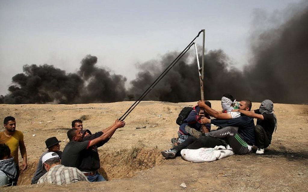 A group of Palestinians man a large sling to hurl stones during clashes with Israeli forces across the border, east of Gaza City, on April 20, 2018. (AFP Photo/Mohammed Abed)
