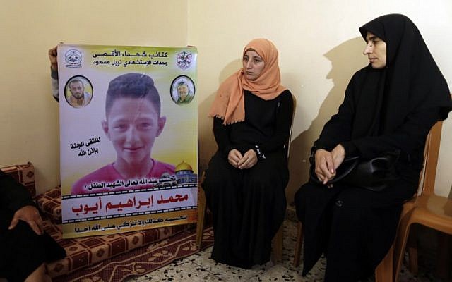 The mother (C) of 15-year-old Palestinian Mohammed Ibrahim Ayoub, who was reportedly shot and killed by the IDF during clashes along the Israel-Gaza border, sits as another person raises his portrait, among other relatives as they mourn in their home in Beit Lahia in the northern Gaza strip on April 21, 2018. (AFP PHOTO / MAHMUD HAMS)