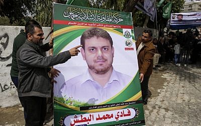 A picture taken on April 21, 2018 shows men holding up a poster portrait of 35-year-old Palestinian professor and Hamas member Fadi Mohammad al-Batsh who was killed in Malaysia, outside his family's house in Jabaliya in the northern Gaza strip. (AFP Photo/Mahmud Hams)