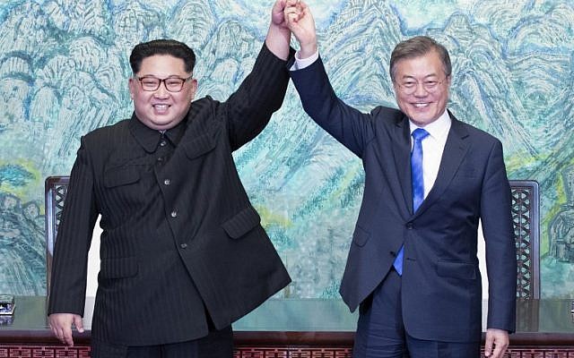 North Korea's leader Kim Jong Un (L) and South Korea's President Moon Jae-in (R) raise their joined hands during a signing ceremony near the end of their historic summit at the truce village of Panmunjom on April 27, 2018. (AFP/Korea Summit Press Pool/Korea Summit Press Pool)