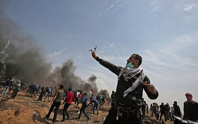 A Palestinian demonstrator uses a slingshot to hurl stones towards Israeli security forces near the southern Gaza Strip town of Khan Younis during the fifth straight Friday of mass demonstrations and clashes along the Gaza-Israel border on April 27, 2018. (AFP Photo/Said Khatib)