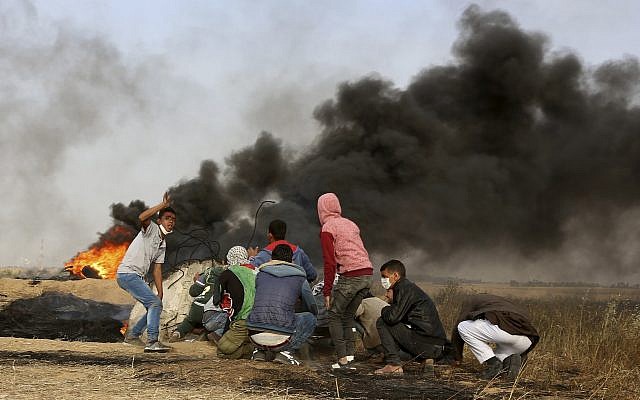 Palestinian protesters cover during clashes with Israeli troops along Gaza’s border with Israel, east of Khan Younis, Gaza Strip, Thursday, April 5, 2018. (AP Photo/Adel Hana)