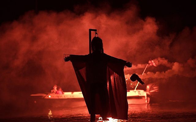 People on a boat hold flares as they sail behind the effigy of Judas during the revival of the old Easter tradition of the "burning of the Judas," in the port town of Ermioni, in the Peloponnese peninsula, southwest of Athens, April 8, 2018. (AP Photo/Petros Giannakouris)