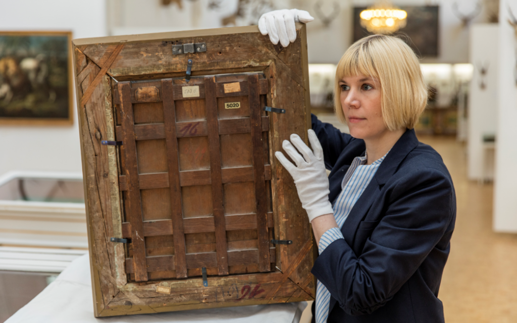 Carolin Lange inspecting the back/the frame of an oil painting. (Landesstelle für die nichtstaatlichen Museen in Bayern)