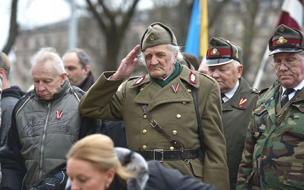 A man dressed in a pre-WWII Latvian military uniform salutes as veterans of the Latvian Legion, a force that was commanded by the German Nazi Waffen SS during WWII, and their sympathizers  walk to the Monument of Freedom in Riga, Latvia on March 16, 2016. (Ilmars Znotins/AFP/Getty Images/via JTA)