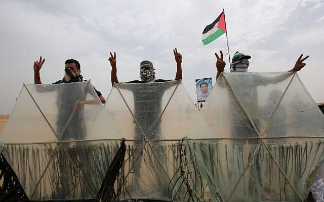 Palestinians pose behind kites before trying to fly them over the border fence with Israel, in Khan Younis in the southern Gaza Strip on May 4, 2018. Palestinians taking part in weekly clashes on the border have adopted a new tactic of attaching firebombs to kites to fly over the border fence into Israel. (AFP Photo/Said Khatib)