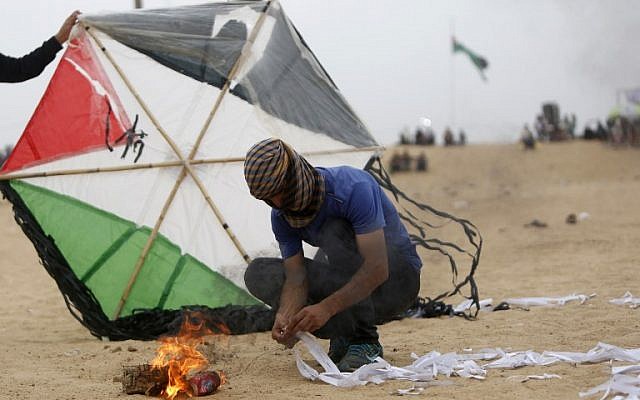 A Palestinian man prepares an incendiary device attached to a kite before trying to fly it over the border fence with Israel, on the eastern outskirts of Jabalia in the Gaza Strip, on May 4, 2018. (Mohammed Abed/AFP)