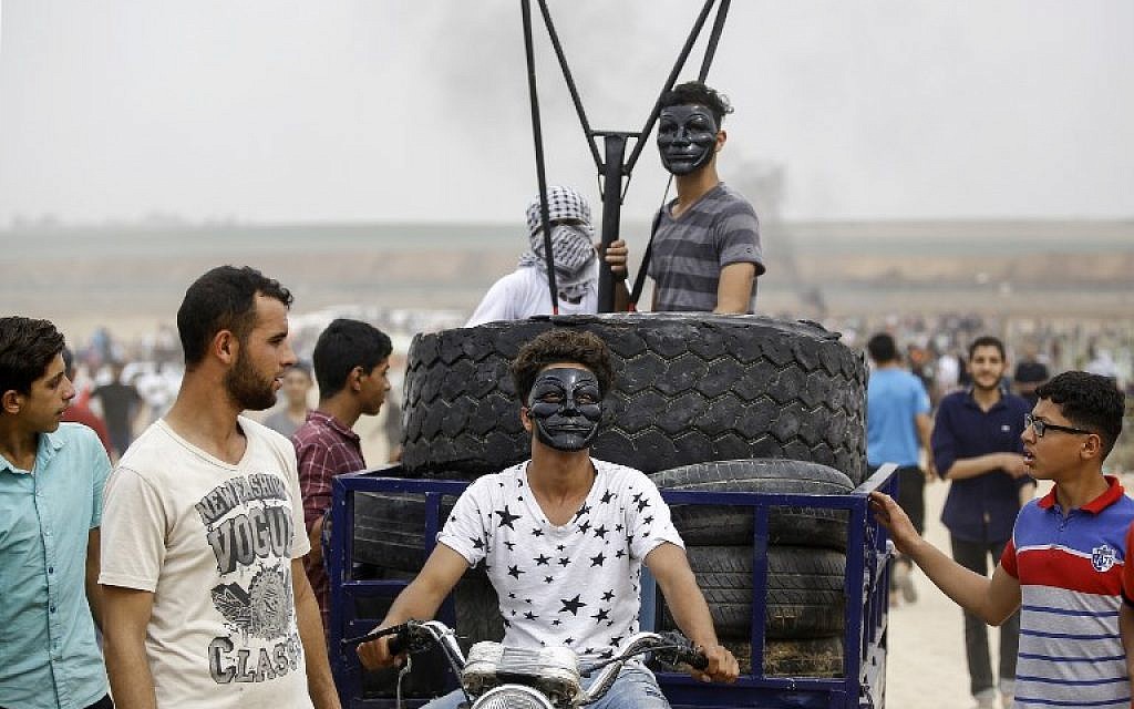 Palestinians ride in the back of a motorcycle cart carrying tires to be burned and a small catapult to hurl stones towards Israeli forces, during clashes near the border between the Gaza Strip and Israel, east of Jabaliya, on May 4, 2018. (AFP Photo/Mohammed Abed)