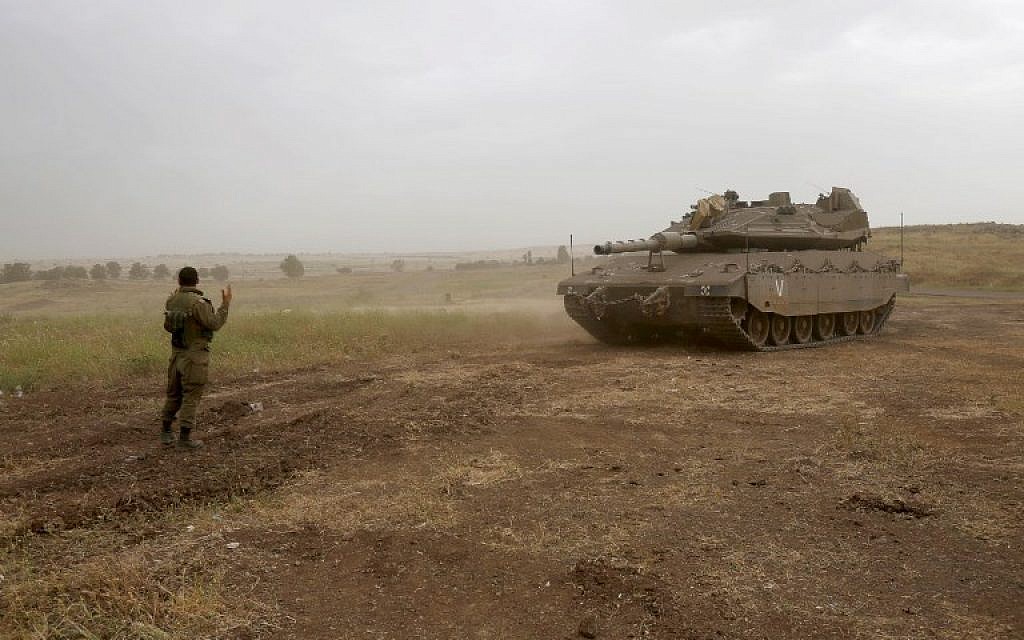 An Israeli soldier directs a Merkava Mark IV tank during a military exercise in the Golan Heights on May 7, 2018. (Jalaa Marey/AFP)