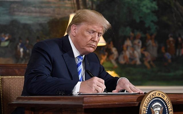 US President Donald Trump signs a document reinstating sanctions against Iran after announcing the US withdrawal from the Iran Nuclear deal, in the Diplomatic Reception Room at the White House in Washington, DC, on May 8, 2018. (AFP/Saul Loeb)