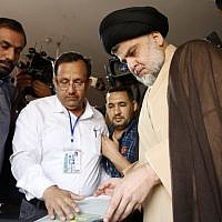 Iraqi Shiite cleric and leader Moqtada al-Sadr (C-R) casts his ballot at a polling station in the holy city of Najaf on May 12, 2018. (AFP Photo/Haidar Hamdani)