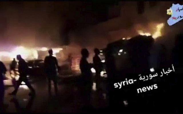 This frame grab from video provided on Wednesday, May, 9, 2018 by Syria News, shows people standing in front of flames rising after an attack on an area known to have numerous Syrian army military bases, in Kisweh, south of Damascus, Syria on Tuesday. (Syria News, via AP)